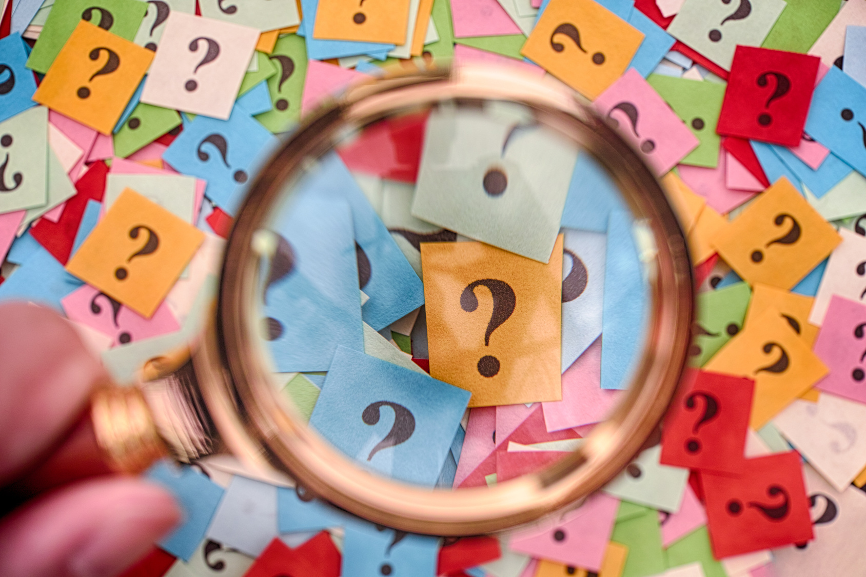 Pile of question marks and magnifying glass