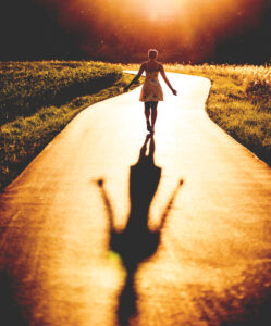 Woman walking towards light with her shadow